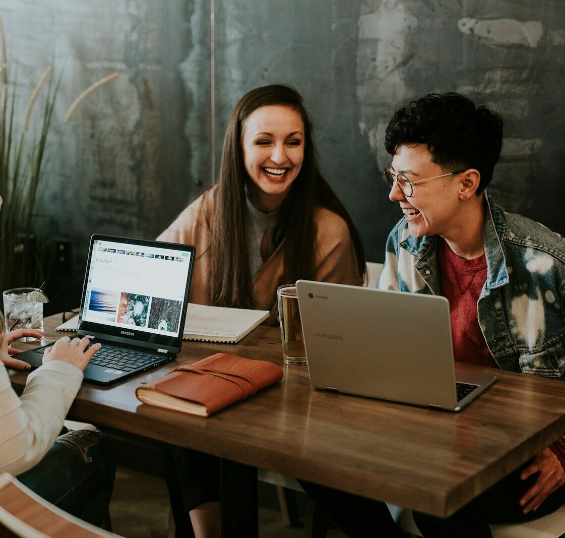 three people sitting in front of table laughing together